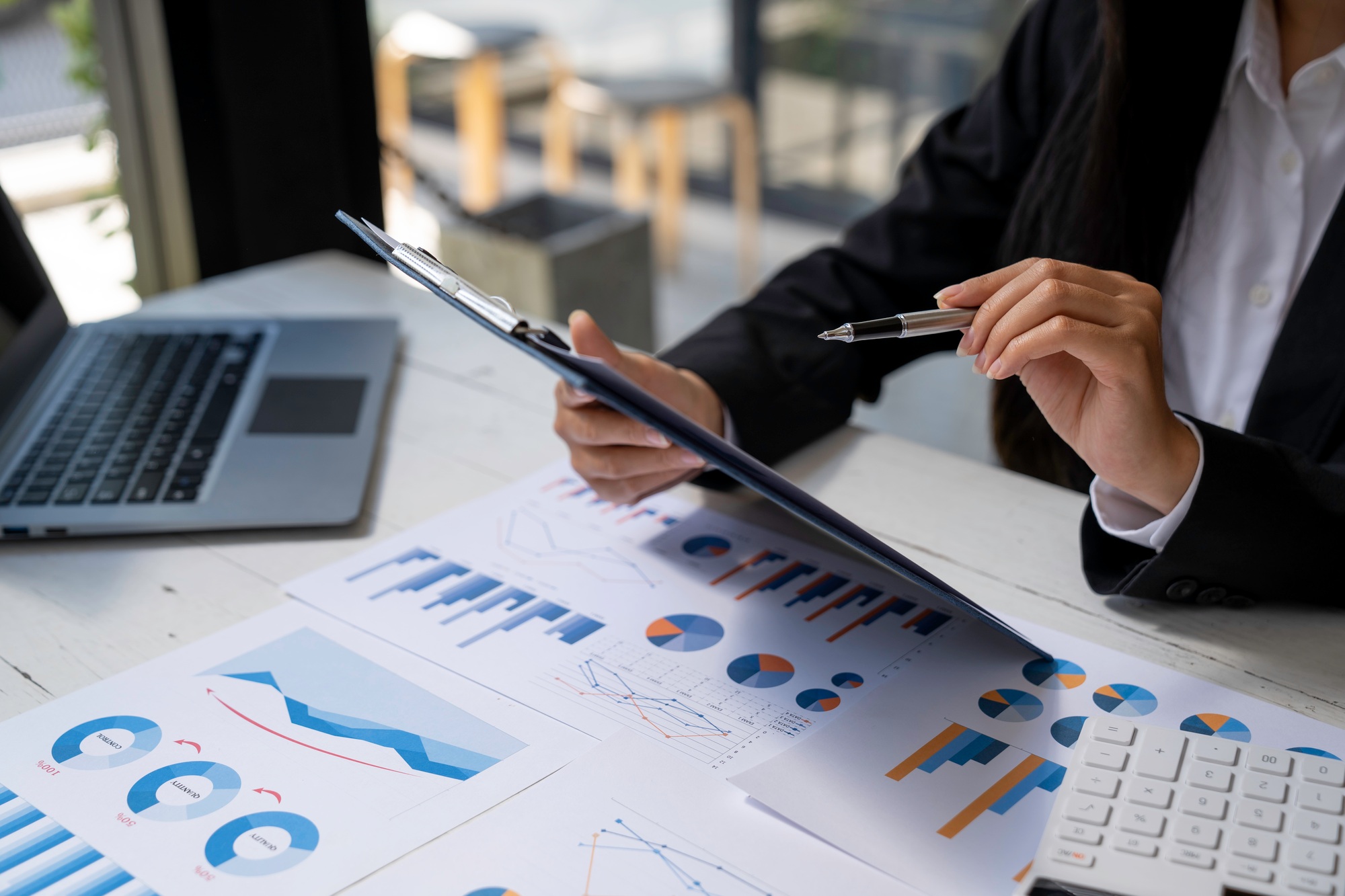 Businesswoman hold graph pens and use a calculator for the company's improvement plan.